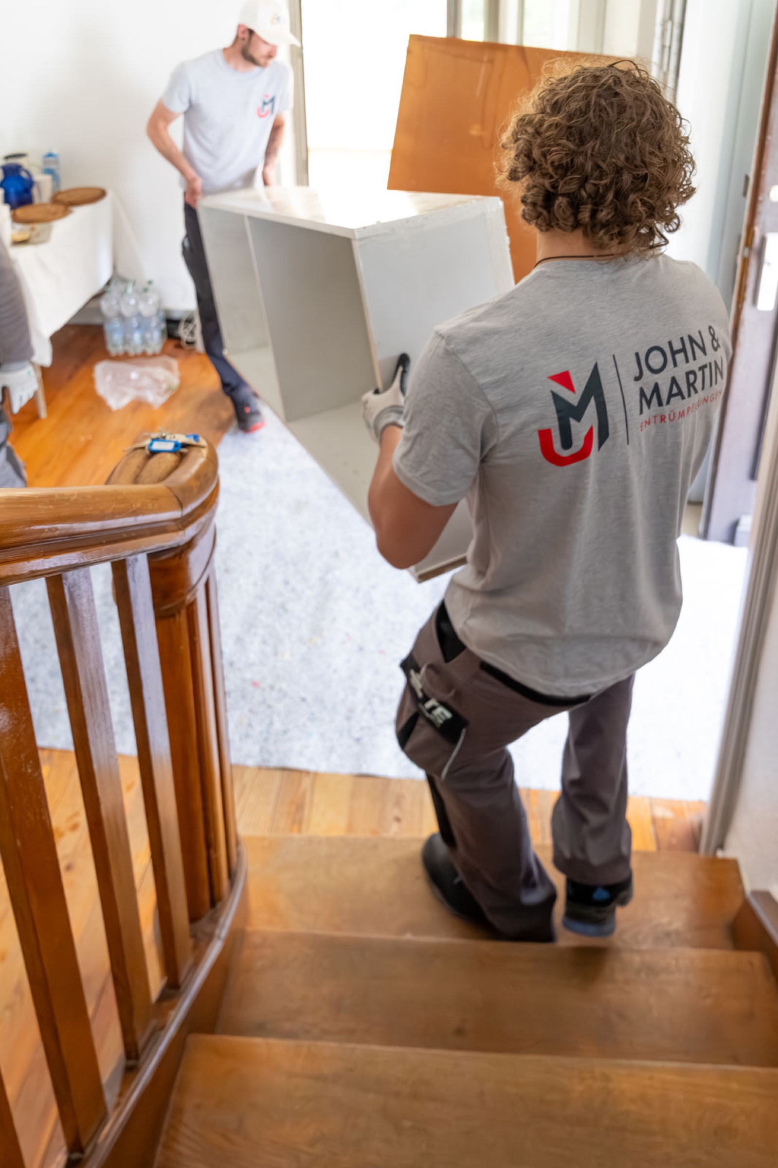 Mitarbeiter trägt Möbel über eine geschützte Holztreppe